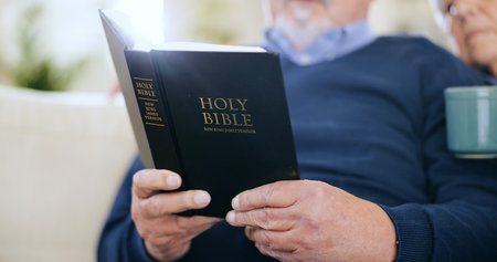 Hands, reading book or old couple with bible, hope or support in Christianity religion with faith or peace. Closeup, holy prayer or elderly person learning God in spiritual literature in retirementの写真素材