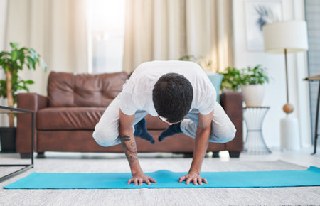 Yoga transformed me mentally and physically. a handsome young man practising yoga in his living room at home.の写真素材