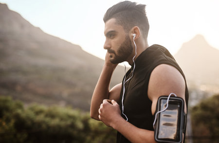 Plug in and get moving. a sporty young man listening to music while exercising outdoors.の写真素材