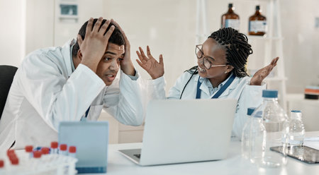 Could this be it. two scientists looking surprised while working together on a laptop in a lab.