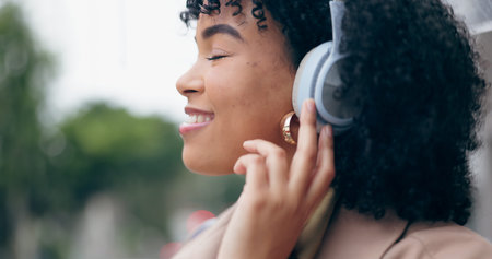 Businesswoman, headphones and listening to music with eyes closed on street, city or outside by...