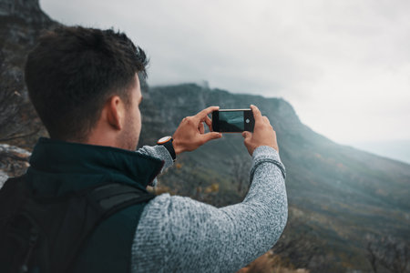 What we see mainly depends on what we look for. a young man taking photos while out on a hike.の写真素材