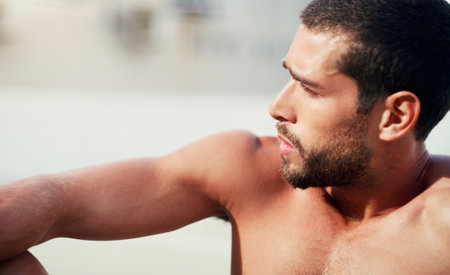 Taking a much needed breather. a handsome shirtless young sportsman sitting down while taking a break after a workout outdoors.の写真素材