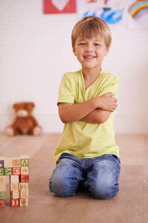 Future civil engineer. A little boy sitting proudly next to a tower he built.