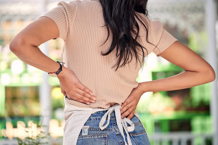 Long days are hard on your body. an unrecognizable worker experiencing pain in her back while at...