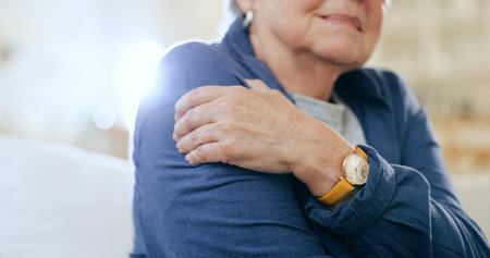Closeup, shoulder pain and old woman with injury, accident and emergency with muscle tension, lens flare and strain. Pensioner, elderly lady or pensioner with stress, bruise and broker with arthritisの写真素材
