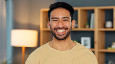Happy, portrait and asian man in a living room at night with confidence, good mood and chilling in his home. Face, smile and Japanese male person in a house in the evening relax, cheerful or positiveの写真素材
