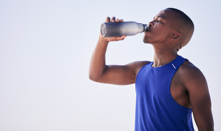 Fitness, black man and drinking water outdoor for training, running and morning cardio on mockup space. Exercise, break and African male person and runner with drink for hydration, health and workoutの写真素材