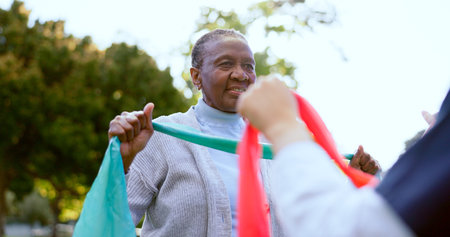 Senior woman, stretching band or nurse outdoor for exercise, workout or fitness in a park and...