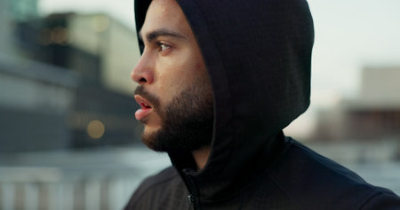 Fitness, face and thinking, man in city on rest from morning workout challenge in hoodie. Relax, breathing and tired athlete on calm urban exercise with fatigue, reflection and outdoor fresh air.の写真素材