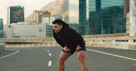 Man, athlete and breathe in road for fitness, exercise or wellness with city background or nature. Runner, person and break or tired for workout, training and healthy body with sportswear in streetの写真素材