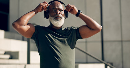 Fitness, music headphones and black man on stairs in city, workout and exercise for body health. Radio, steps and senior athlete in urban town, listening to audio sound and serious, thinking or relaxの写真素材