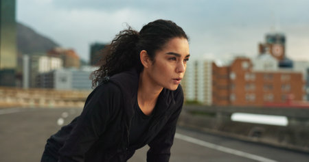 Woman, athlete or breathe outdoor for fitness, exercise or wellness and city background or nature. Runner, person or tired or break for workout, training and healthy body with sportswear in town roadの写真素材