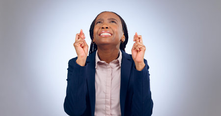 Business woman, fingers crossed and hope in studio for luck, thinking of wish or waiting for...