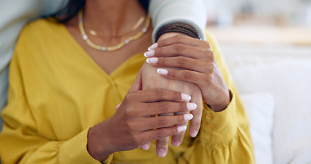 Couple, closeup and holding hands on sofa in home living room together for support, bonding and love with care. People, helping and consulting for empathy, kindness and connection with trust in houseの写真素材