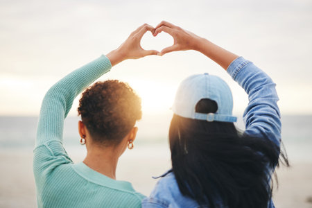 Love, beach and lesbian couple with heart hands at sunset, summer holiday adventure or date...