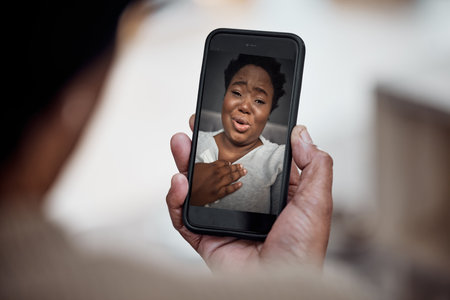 Video call, communication and black woman on a phone screen with internet connection at home. Online conversation, talking and smartphone in hands of a person for distance chat, call and povの写真素材