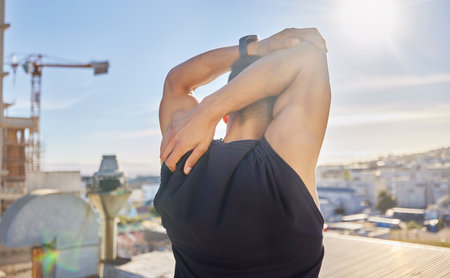 This is my workout routine. a sporty young man stretching while on a rooftop.の写真素材