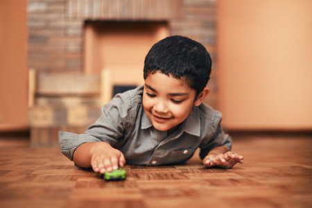 Watch how fast my car can go. an adorable little boy playing with a toy car at home.の写真素材