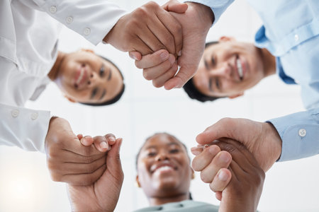 Diversity, support and collaboration of business people holding hands below in trust for company success. Team of corporate workers in a circle of success in a meeting together at a corporate companyの写真素材
