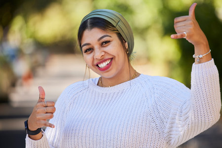Muslim, thumbs up and portrait of woman student with yes, agreement and okay gesture on university or college campus. Smile, happy and young female person with thank you sign or symbol in a parkの写真素材