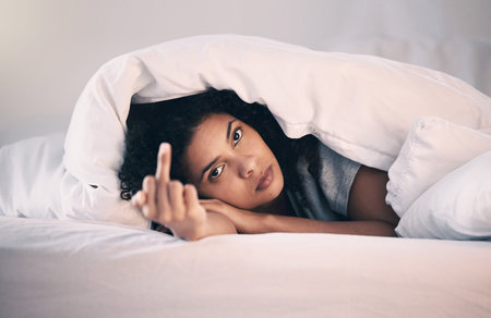 Angry, woman with insomnia and portrait in bed with a middle finger for morning or waking up,...