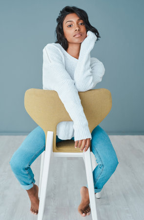 Theres power in loving yourself. a beautiful young woman sitting on a chair against a teal...