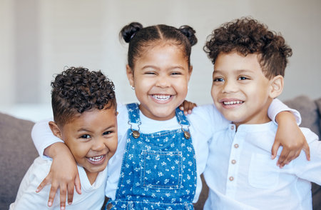 Three happy and adorable mixed race kids having fun and laughing together at home. Group of boys and girl siblings or cousins playing and bonding while growing up together. The innocence of childhoodの写真素材