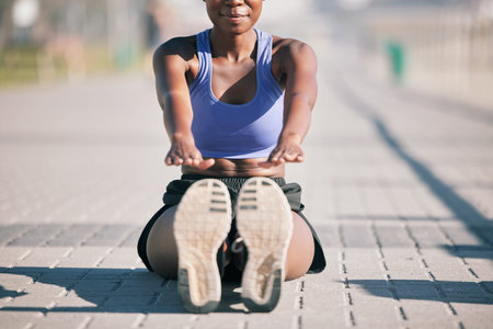 Sports woman, legs and stretching to touch feet for fitness, training and performance on urban ground. Shoes, female athlete and warm up for workout, muscle mobility and flexible exercise of runnerの写真素材