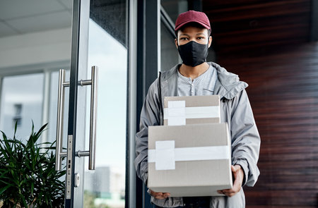 Wherever you are, well get it delivered. a masked young man delivering a package to a place of...