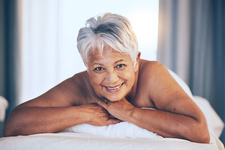Happy senior woman, portrait and massage in relax for spa treatment, body care and physical therapy at resort. Calm elderly female person smile relaxing on salon bed for zen, stress relief or getawayの写真素材