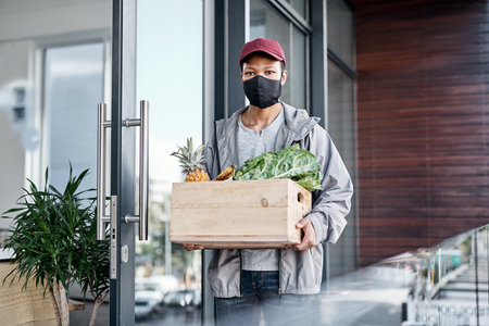 Fresh produce delivered right to your front door. a young man delivering fresh produce to a place of residence.の写真素材