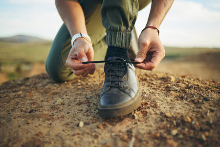 Hands, tie shoes and hiking in nature for travel, training or adventure outdoor. Fitness, sports and...