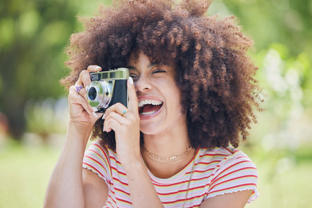 Photographer, happy and woman with a camera in nature enjoying taking pictures of a natural environment. Smile, happiness and Afro girl outdoors shooting creative shots as a freelancer in photographyの写真素材