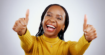 Thumbs up, excited black woman and portrait in studio for success, winning deal and achievement on...