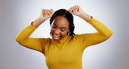 Dance, celebration and happy black woman in studio with freedom, feel good or music on grey...