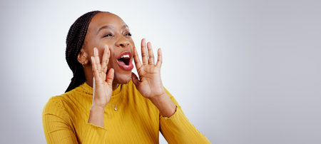 News, announcement and happy black woman shouting in studio for coming soon, deal or info on grey background. Screaming, excited and female model with emoji for giveaway, sale or sign up motivationの写真素材