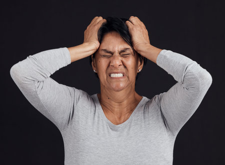Anger, anxiety and senior woman screaming, depression and mental health issue on a dark studio...