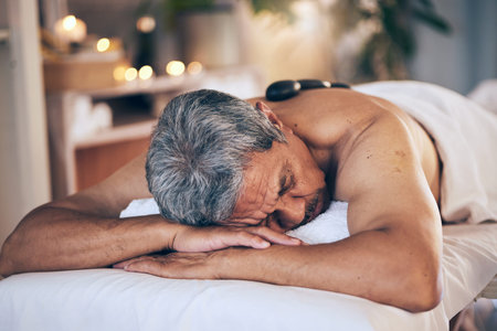 Senior man, sleeping and relax in massage for spa treatment, body care and physical therapy at...