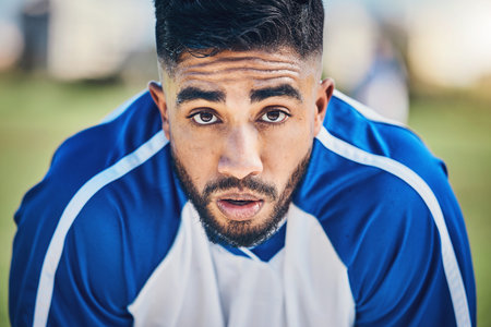 Soccer player, tired or portrait of man in sports training, game or match breathing heavy on a field pitch. Face, fatigue or exhausted male athlete in football workout or fitness exercise on breakの写真素材