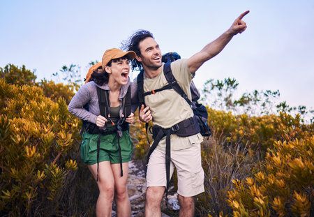 Hiking, pointing and excited couple in nature for adventure, holiday and journey on mountain. Travel, dating and man and woman walking with surprise and wow for view, trekking and backpacking outdoorの写真素材