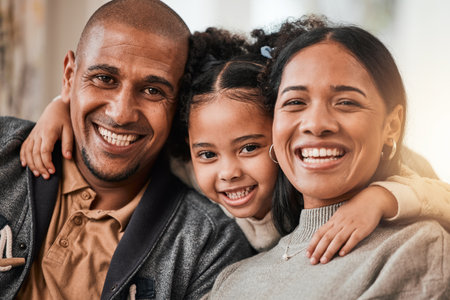 Happy, hug and portrait of a child with her parents in the living room of their family home. Happiness, smile and sweet girl kid holding her mother and father in the lounge of her modern house.の写真素材