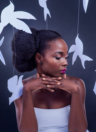 Go forth and dazzle. Studio shot of a beautiful young woman posing with paper birds against a black...