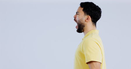 Scream, angry and man in studio at mockup space for crisis, conflict and mad emoji reaction on white background. Profile of frustrated indian model shouting with stress, anger and negative expressionの写真素材