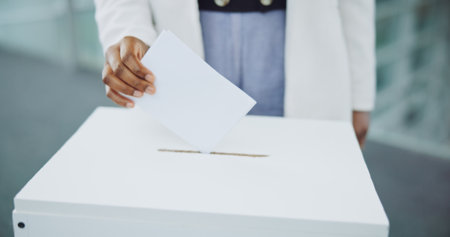 Hand, ballot and box for vote paper at president election cast, poll station choice or government selection. Person, fingers and decision document or politics support or usa process, opinion at boothの写真素材