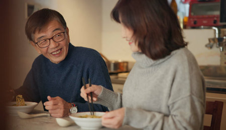 Japanese couple, food and home with conversation, love and bonding together with happiness, romance and smile. Apartment, old man or senior woman with healthy meal, nutrition and cheerful with dinnerの写真素材