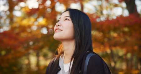 Woman, forest and enjoy in Kyoto, garden and tourist with happiness, traditional history and travel. Nature, japanese culture and explore in woods with trees, adventure and holiday walk in autumnの写真素材