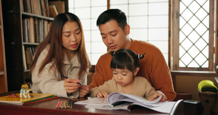 Japanese family, education and learning for school with homework in living room of apartment. Study, growth or child development with student girl, mother and father in home together for knowledgeの写真素材