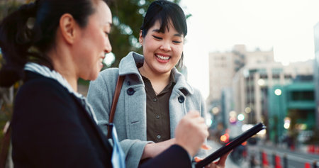 Asian woman, tablet and team in city of Japan for communication, research or social media together. Business people smile on technology for online search, chat or networking on sidewalk in urban townの写真素材