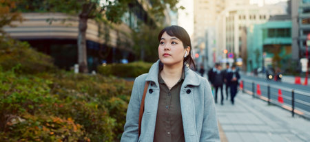 Woman, Asian and walking, travel or commute to work with professional in city with earphones. Listening to music on journey, podcast and commuter on urban street or sidewalk in Tokyo with playlistの写真素材